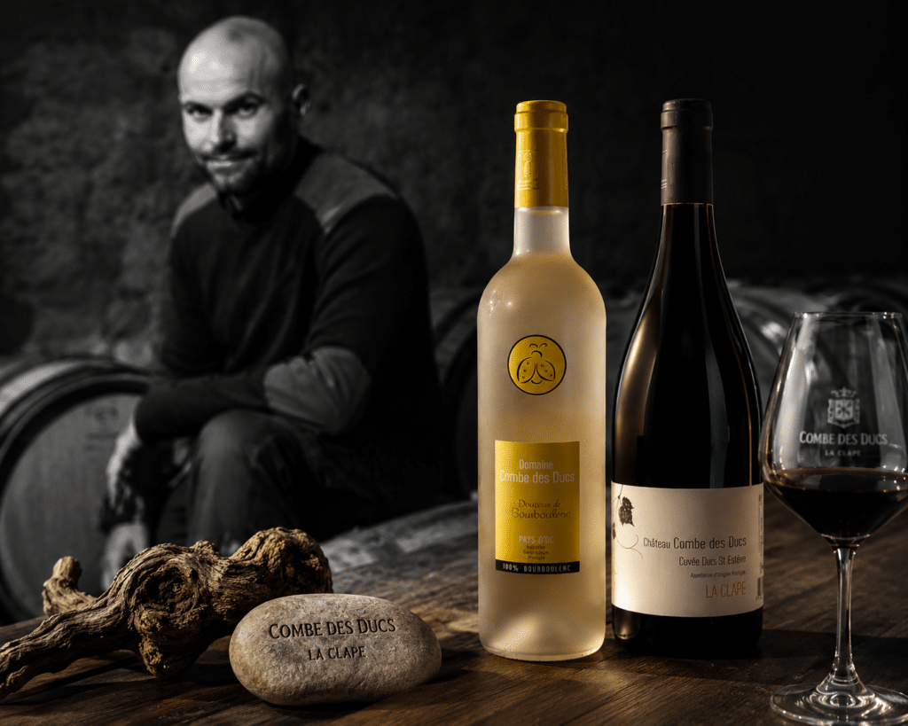 Bouteilles de vin Combe des Ducs, blanc et rouge, avec verre et vigneron en cave à La Clape.
